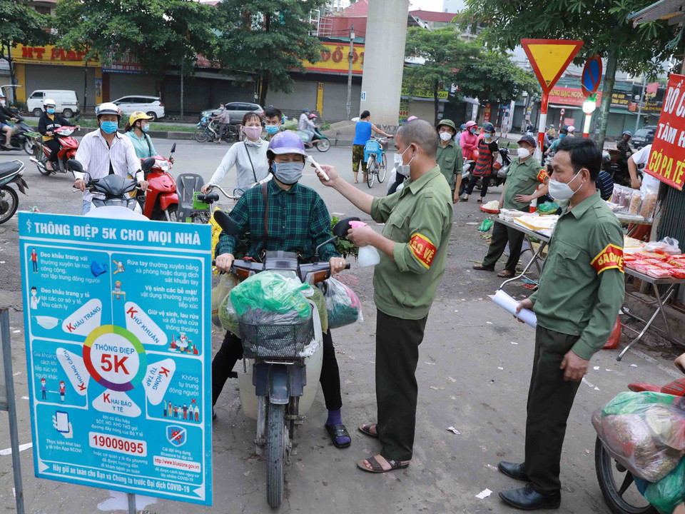 Ban Quản lý chợ đầu mối Minh Khai tổ chức đo thân nhiệt cho người dân khi đến chợ. (Ảnh: Vũ Sinh/TTXVN)