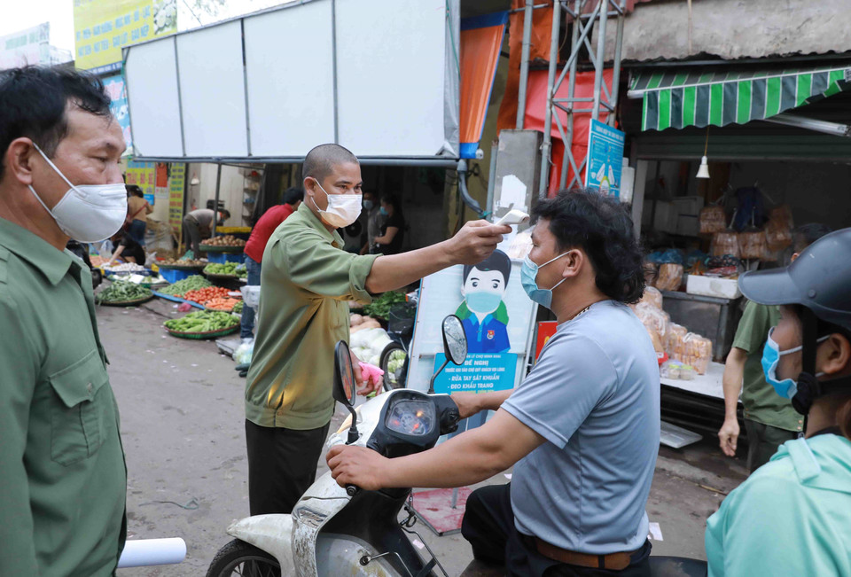 Ban Quản lý chợ đầu mối Minh Khai tổ chức đo thân nhiệt cho người dân khi đến chợ. (Ảnh: Vũ Sinh/TTXVN)