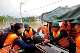Đại tá Nguyễn Văn Hòa, Phó Tham mưu trưởng Quân khu 5, trực tiếp trao nhu yếu phẩm thiết yếu cho người dân vùng ngập lũ. (Ảnh: Đoàn Hữu Trung/TTXVN)