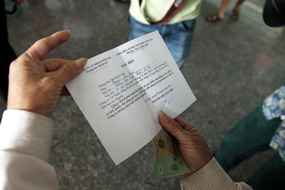 Người lao động nhận tiền hỗ trợ và giấy hẹn lên công ty thanh lý hợp đồng. (Ảnh: Doãn Đức/Vietnam+)