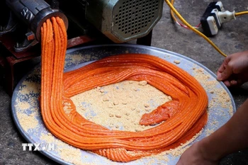 Xôi gấc làm bánh giầy được xay nhuyễn, có màu cam đỏ. (Ảnh: Thanh Hải/TTXVN)