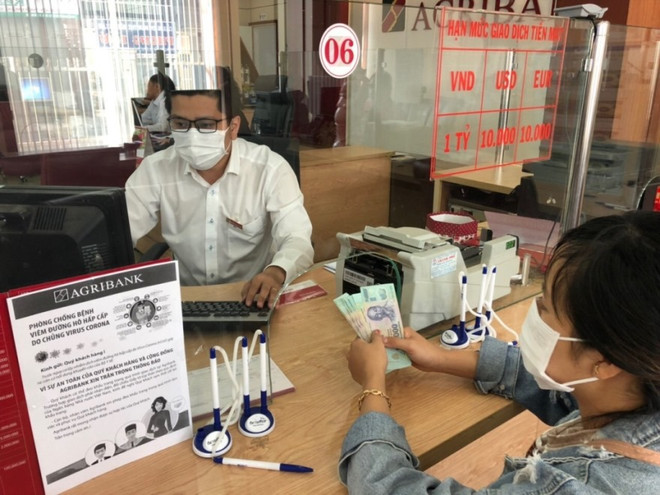 Giao dịch tại ngân hàng. (Ảnh: Vietnam+) Hỗ trợ khách hàng bị ảnh hưởng dịch: Ngân hàng vào cuộc giảm lãi suất ảnh 2