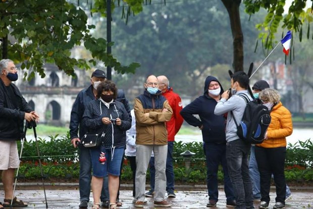 Du khách nước ngoài đeo khẩu trang khi đi tham quan Hà Nội. (Ảnh: Minh Quyết/TTXVN) Các biện pháp đảm bảo an toàn trong cơ sở kinh doanh và du lịch ảnh 1