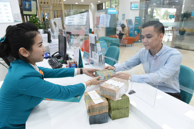 Giao dịch tại ngân hàng. (Ảnh: Vietnam+) Ngân hàng đua giảm lãi suất huy động dưới 6 tháng xuống mức trần 5% ảnh 1