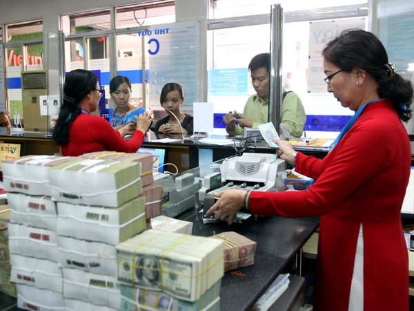 Giao dịch tại ngân hàng. (Nguồn: TTXVN). Ngân hàng "tranh thủ" hút dòng tiền ngày cận Tết ảnh 1