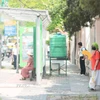 Quạt, khăn ướt phủ đầu...là cách của người dân chọn khi đợi xe buýt. (Ảnh: Lê Đông/TTXVN)
