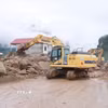 Các phương tiện máy móc tập trung san gạt cây cối, đất đá góp phần thông đường tạm thời cho nhân dân đi lại. (Ảnh: Quý Trung/TTXVN)