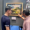 Đại sứ Trần Phước Anh (phải) giới thiệu tranh của Việt Nam với ông Baey Yam Keng - Quận trưởng quận Đông Bắc. (Ảnh: Đỗ Vân/TTXVN)