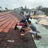 Lũ dâng cao, người dân phải phá mái nhà leo lên để tránh nguy hiểm. (Ảnh: TTXVN phát)