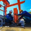 Công nhân thi công lắp đặt cấu kiện trên mái đập. (Ảnh: Trọng Đạt/TTXVN)
