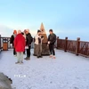 Du khách thích thú khi được trải nghiệm băng giá trên đỉnh Fansipan. (Ảnh: TTXVN phát)