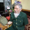 Ông Nguyễn Thế Tám nâng niu chiến tích tịch thu được của quân địch trong thời gian tham gia giải phóng Sài Gòn. (Ảnh: Công Luật/TTXVN)