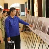 Cán bộ Đoàn và sỹ quan công an Lào tham quan khu trưng bày ảnh về Chiến dịch Hồ Chí Minh lịch sử của Việt Nam. (Ảnh: Xuân Tú/TTXVN)