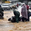 Lực lượng dân quân hỗ trợ một người điều khiển xe máy bị ngã khi đi qua đoạn đường ngập nước trước cổng Vườn hoa thành phố Đà Lạt. (Ảnh: Nguyễn Dũng/TTXVN)