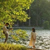 Các bạn trẻ lưu lại khoảnh khắc mùa Thu Hà Nội tại hồ Hoàn Kiếm. (Ảnh: Khánh Hòa/TTXVN)