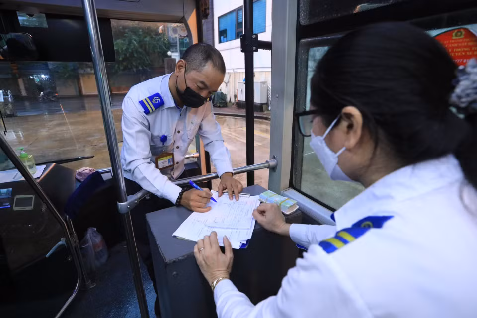 Lái xe Hoàng Quốc Bảo và nhân viên bán vé tuyến xe buýt BRT 01 Kim Mã-Yên Nghĩa ký lệnh điều động xe xuất bến Kim Mã. (Ảnh: Tuấn Anh/TTXVN)