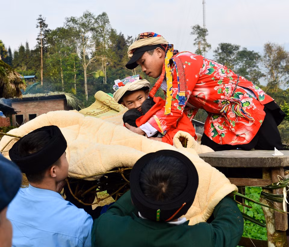 Trải qua các nghi thức, người được Cấp Sắc được thầy đưa xuống võng được bện bằng dây leo, lót bằng chăn, chiếu mới. (Ảnh: Nam Thái/TTXVN)