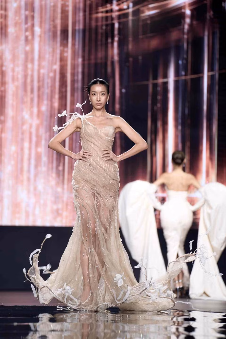 Voan lưới và organza xuyên thấu được đặt cạnh những cấu trúc cứng cáp, tạo thế giằng co giữa vẻ thướt tha và tinh thần mạnh mẽ. Phom dáng mềm mại của Khởi Vũ nhường chỗ cho hình khối, đường cắt sắc nét và cấu trúc gọng định hình cơ thể, gợi sức nặng của bầu trời trong cơn giông. (Ảnh: CTV/Vietnam+)