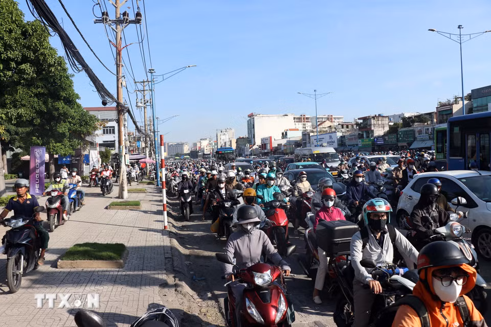 Nhiều người đi xe máy chạy lên vỉa hè để di chuyển khi đường ùn ứ. (Ảnh: Tiến Lực/TTXVN)