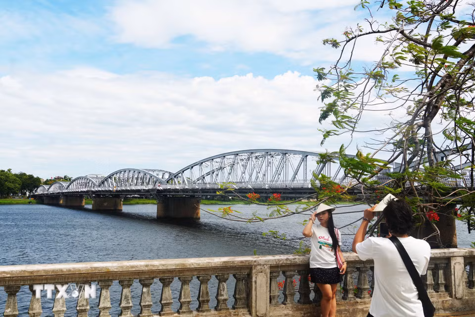 Du khách chụp ảnh bên cầu Trường Tiền. (Ảnh: Nguyên Lý/TTXVN)