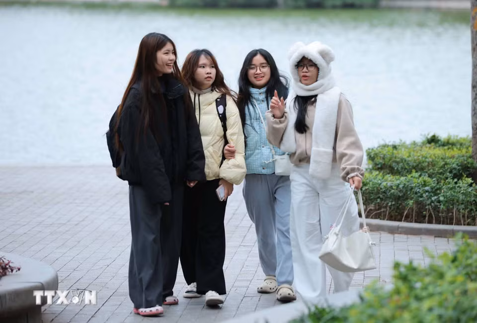 Người dân ra đường đều mặc áo ấm, khăn quàng cổ để đảm bảo sức khoẻ khi phải ra ngoài trời. (Ảnh: Hoàng Hiếu/TTXVN)