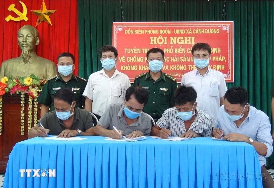Ký cam kết giữa Đồn Biên phòng Roòn, UBND xã Cảnh Dương và các hộ ngư dân Quảng Bình về “Khai thác hải sản bất hợp pháp, không khai báo và không theo quy định” (IUU). (Ảnh: Đức Thọ/TTXVN)