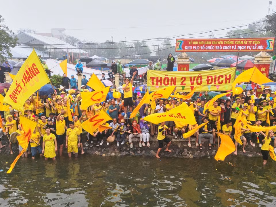 Cổ động viên Thôn 2 cổ vũ cho đội đua thuyền của địa phương. (Ảnh: Lê Đông/TTXVN)