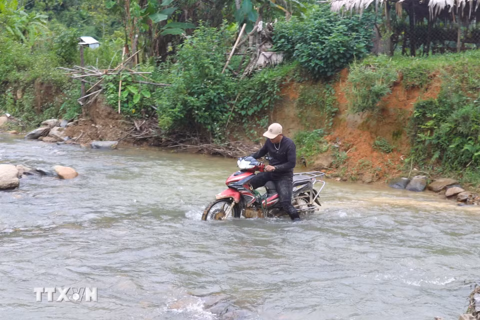 Người dân vất vả đưa xe máy qua đoạn suối Nậm Ngân giao cắt với tuyến đường vào trung tâm bản Na Ngân (xã Nga My, Nghệ An). (Ảnh: Xuân Tiến/TTXVN)