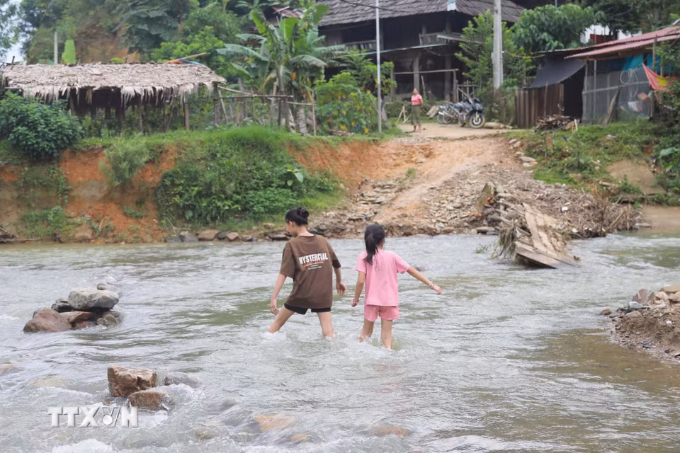 Không còn cầu tạm nối giữa 2 cụm dân cư của bản, trẻ em trong bản Na Ngân (xã Nga My, Nghệ An) vất vả khi lội qua suối Nậm Ngân để trở về nhà. (Ảnh: Xuân Tiến/TTXVN)