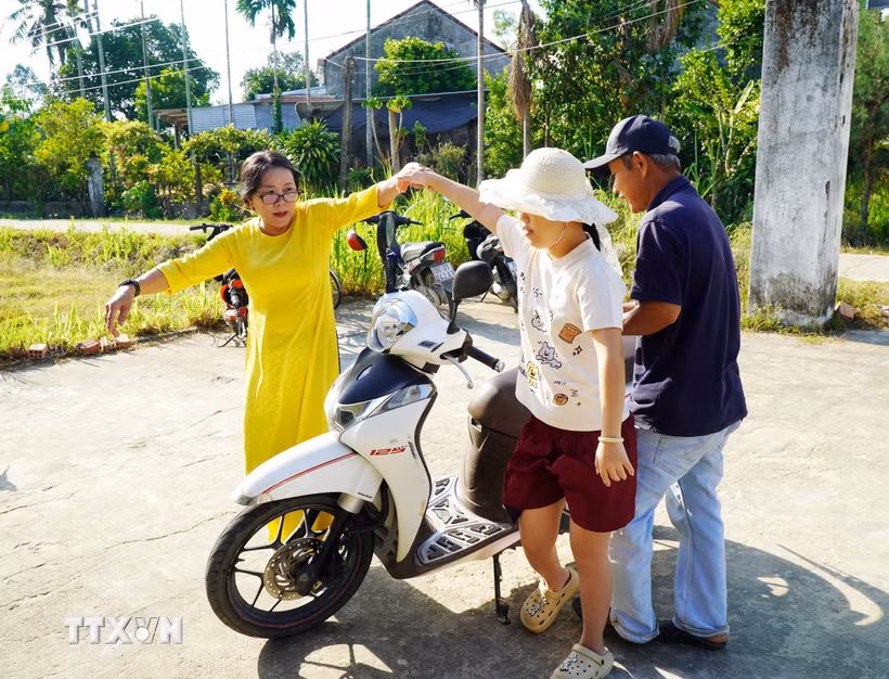 Thầy cô, người thân dìu các em khuyết tật vào dự lễ khai giảng. (Ảnh: Lê Phước Ngọc/TTXVN)