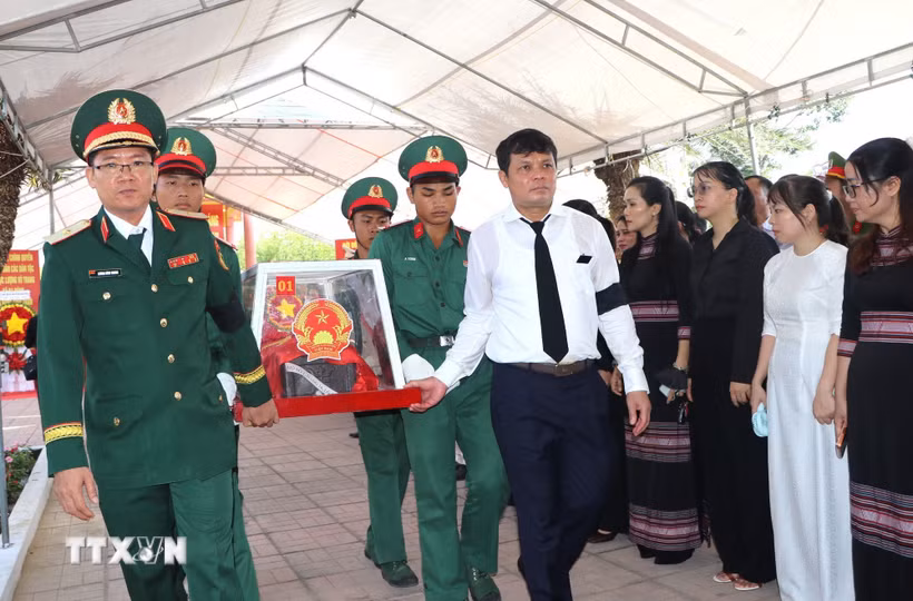 Thiếu tướng Lương Đình Chung, Bí thư Đảng uỷ Chính uỷ Quân khu và đồng chí Nguyễn Đức Tuy, Phó Bí thư Tỉnh uỷ, Chủ tịch HĐND tỉnh Quảng Ngãi, đưa liệt sĩ về nơi an nghỉ. (Ảnh: Đinh Hương/TTXVN)