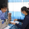 Cán bộ ngân hàng chi trả tiền đền bù giải phóng mặt bằng cho người dân. (Ảnh: Thanh Bình/TTXVN)