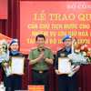 Thượng tướng Lương Tam Quang, Thứ trưởng Bộ Công an trao Quyết định của Chủ tịch nước cho 2 sỹ quan Công an Nhân dân đi thực hiện nhiệm vụ gìn giữ hòa bình Liên hợp quốc. (Ảnh: TTXVN phát)