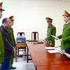 Lực lượng chức năng đọc lệnh khởi tố và bắt tạm giam Trần Quang Anh. (Ảnh: TTXVN phát)