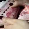 Kiểm tiền mệnh giá 100 nhân dân tệ tại thủ đô Bắc Kinh, Trung Quốc. (Ảnh: AFP/TTXVN)