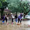 Cán bộ giáo viên trường Tiểu học Tân Hóa (huyện Minh Hóa, Quảng Bình) vệ sinh khuôn viên trường sau khi nước rút. (Ảnh: Tá Chuyên/ TTXVN)