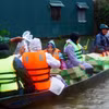 Dùng thuyền vận chuyển nhu yếu phẩm, nước sạch đến người dân các vùng thấp trũng còn bị ngập nước của huyện Lệ Thủy (Quảng Bình). (Ảnh: Tá Chuyên/TTXVN)
