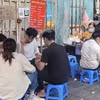 Học sinh, sinh viên hồn nhiên ngồi ăn quán xiên nướng vỉa hè quanh khu vực trường Tiểu học Lê Ngọc Hân, quận Hai Bà Trưng. (Ảnh: Phương Anh/TTXVN)
