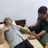 Cán bộ Quân y Đồn Biên phòng Cửa khẩu Cảng Gianh thăm khám sức khỏe ban đầu cho thuyền viên bị nạn Nguyễn Văn Bình. (Ảnh: TTXVN phát)