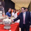 Thủ tướng Phạm Minh Chính thăm gian hàng trưng bày sản phẩm đạt Thương hiệu Quốc gia năm 2022. (Ảnh: TTXVN)