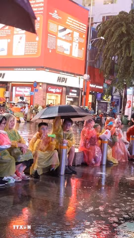 Người hâm mộ Thành phố Hồ Chí Minh đội mưa tập trung tại phố đi bộ Nguyễn Huệ trước trận chung kết lượt về. (Ảnh: Hồng Đạt/TTXVN)