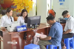Người dân phường Bến Cát được hướng dẫn đăng ký, nộp hồ sơ thủ tục hành chính trực tuyến, thanh toán điện tử và cài đặt, đăng nhập tài khoản VNEID. (Ảnh: Hữu Duyên/TTXVN)