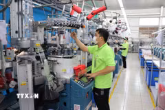 Công nhân nhà máy Sung Hwa Vina (vốn Hàn Quốc) tại Khu Công nghiệp Hòa Bình (Tây Ninh) kiểm tra sợi trên máy dệt tất. (Ảnh: Minh Hưng/TTXVN)