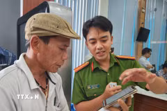 Cán bộ công an hướng dẫn người dân thao tác xin cấp phiếu lý lịch tư pháp trên ứng dụng VNeID. (Ảnh: Mai Trang/TTXVN)