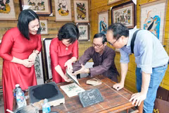 Du khách trải nghiệm in tranh dân gian Đông Hồ (Bắc Ninh). (Ảnh: Đồng Thúy/TTXVN)
