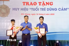 Phó Bí thư Thường trực Tỉnh đoàn Bắc Giang Bùi Văn Hoàng trao tặng Huy hiệu “Tuổi trẻ dũng cảm” cho 2 em là: Phạm Đình Tuấn và Phạm Hoàng Long. (Ảnh: Đồng Thúy/TTXVN)