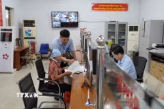 Cán bộ Trung tâm phục vụ hành chính công xã Yên Mỹ hướng dẫn hỗ trợ người già thực hiện thủ tục hành chính. (Ảnh: Mạnh Khánh/TTXVN)