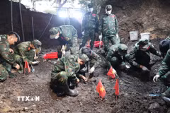 Cán bộ, chiến sỹ đội K74 triển khai công tác tìm kiếm, quy tập hài cốt liệt sỹ tại khu vực rãnh mộ tập thể của liệt sỹ mới được phát hiện. (Ảnh: Xuân Khu/TTXVN)