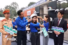 Hướng dẫn đội mũ để lái xe an toàn khi tham gia giao thông. (Ảnh: Minh Đức/TTXVN)