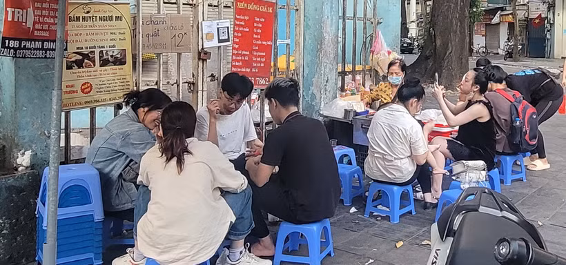 Học sinh, sinh viên hồn nhiên ngồi ăn quán xiên nướng vỉa hè quanh khu vực trường Tiểu học Lê Ngọc Hân, quận Hai Bà Trưng. (Ảnh: Phương Anh/TTXVN)